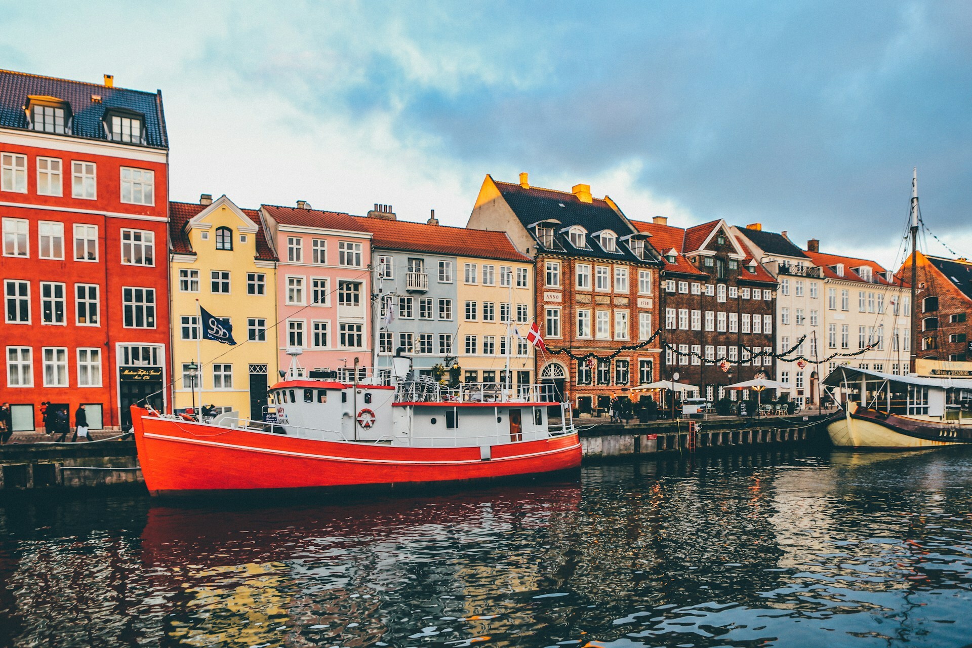 Kolorowe kamienice nad kanałem Nyhavn w Kopenhadze i czerwony statek zacumowany przy nabrzeżu.